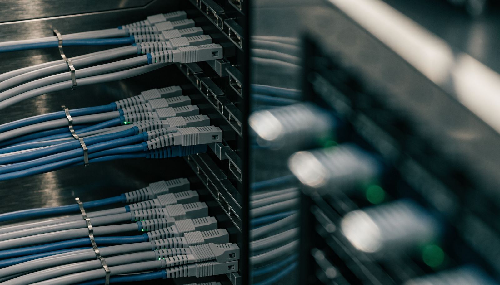 Nahaufnahme sauber verlegter Patchkabel in einem Netzwerkschrank mit leuchtenden Statusanzeigen